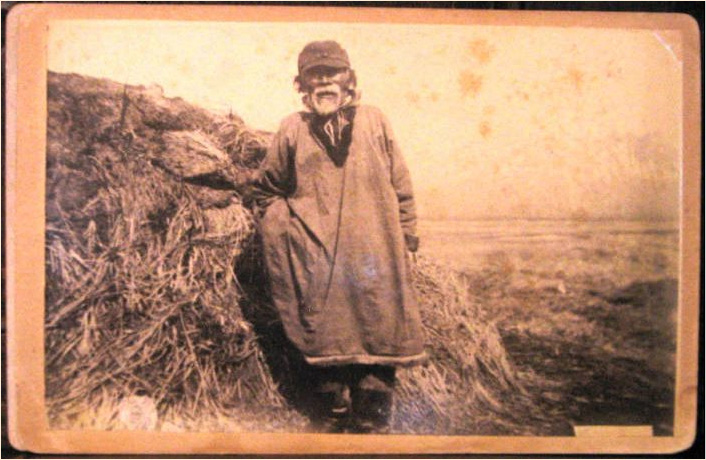 Cabinet card. Unidentified man and
        unidentified location, possibly Alaska. Inupiat or Yup'ik?
        Standing next to a barabara?