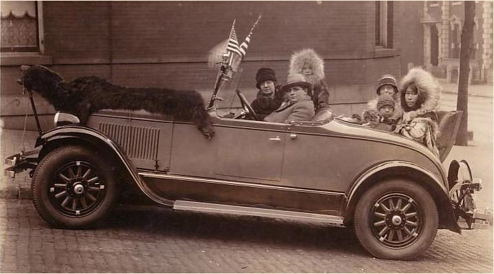 Eskimos in a car with bearskin
        rug on hood. Maybe Seattle?